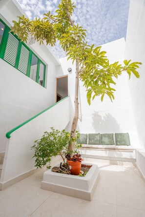 Eine Treppe mit grünen Geländern, einem Blumentopf mit Baum und einer Bank mit weißen Kissen.