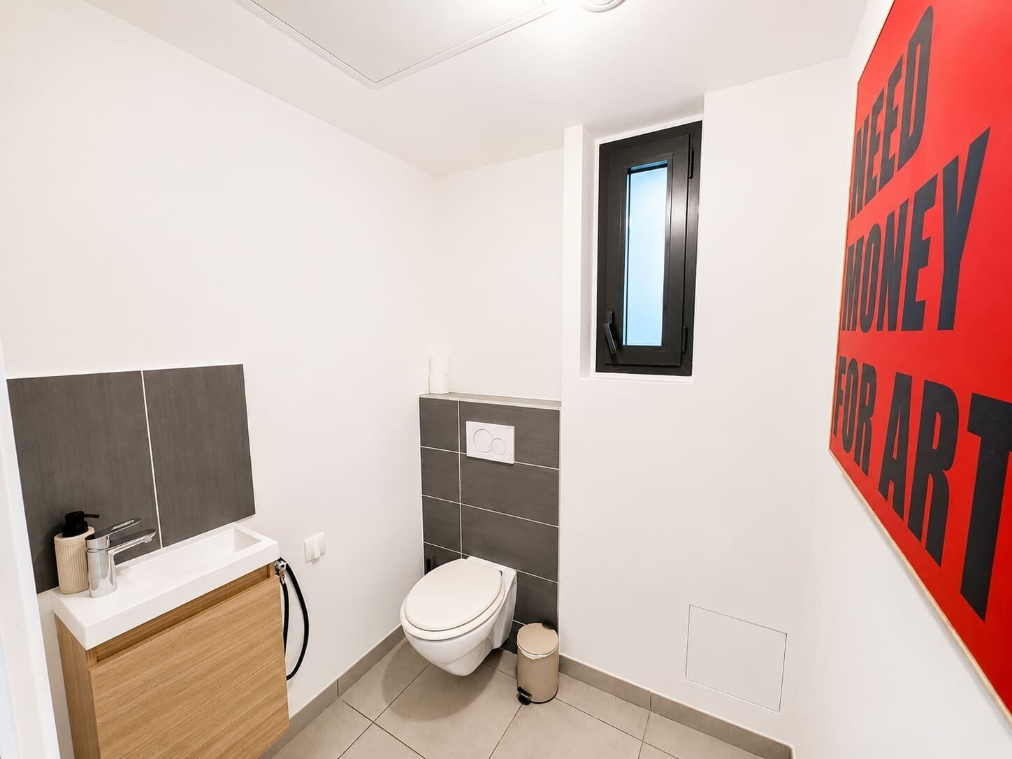 A modern bathroom with a toilet, sink, and a window.