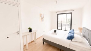 A bedroom with a bed, bedside table, and a window with a view. - Appartement 2 chambres avec terrasse a Courbevoie (Courbevoie)