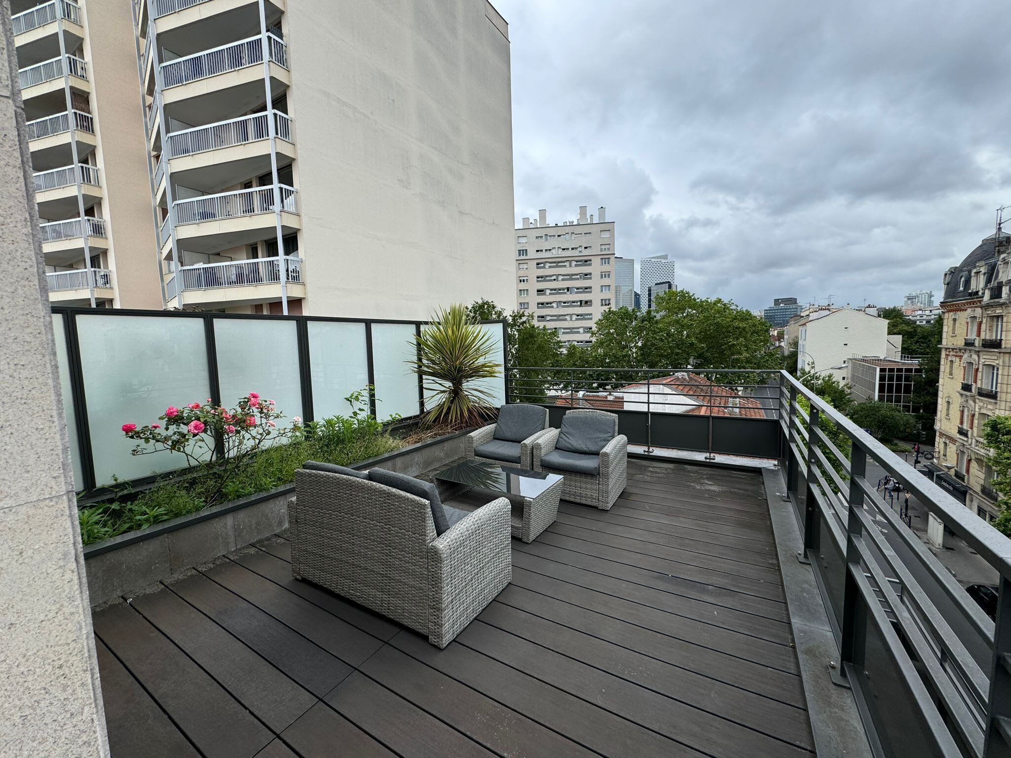 Una terrazza sul tetto con mobili da esterno, vista sulla città e un parapetto in vetro.