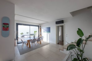 Un espacio habitable moderno con comedor, una escalera y un amplio ventanal.