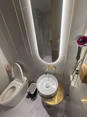 A modern bathroom with a toilet, sink, shower, and a mirror. - City View Room At Vue Aston by VS (Phnom Penh-ភ្នំពេញ)