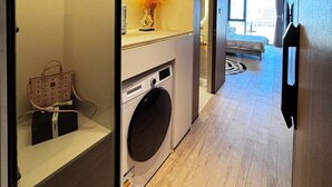 Ein modernes Hotelzimmer mit Waschmaschine, einem Bett und Blick auf die Stadt.