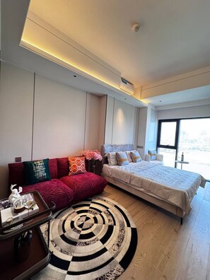 Une chambre dâhĂŽtel moderne Ă©quipĂ©e dâun lit, dâun canapĂ©, dâune petite table avec un plateau, et dâune grande fenĂȘtre.