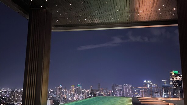Ein Pool auf dem Dach mit Blick auf die Stadt, einer perforierten Decke und einem Holzdeck.