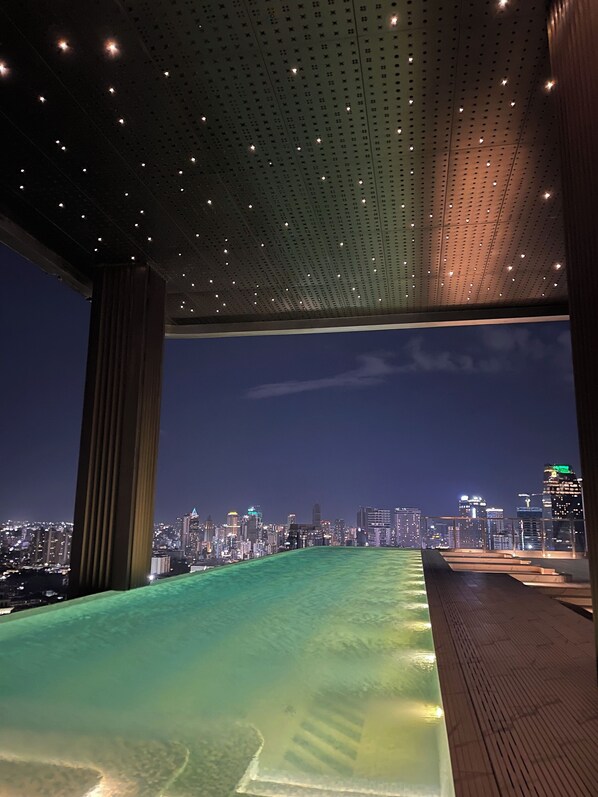 Une piscine sur le toit offrant une vue sur la ville, un plafond ajouré et une terrasse en bois.