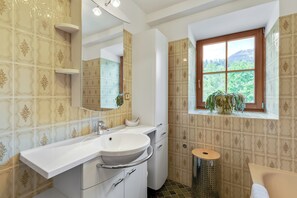 A bathroom with a sink, mirror, window, and a potted plant. - Ferienhaus Auwiese - Family Retreat (Lend)