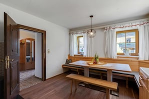 A dining area with a wooden bench, table, and a hanging light fixture. - Ferienhaus Auwiese - Family Retreat (Lend)