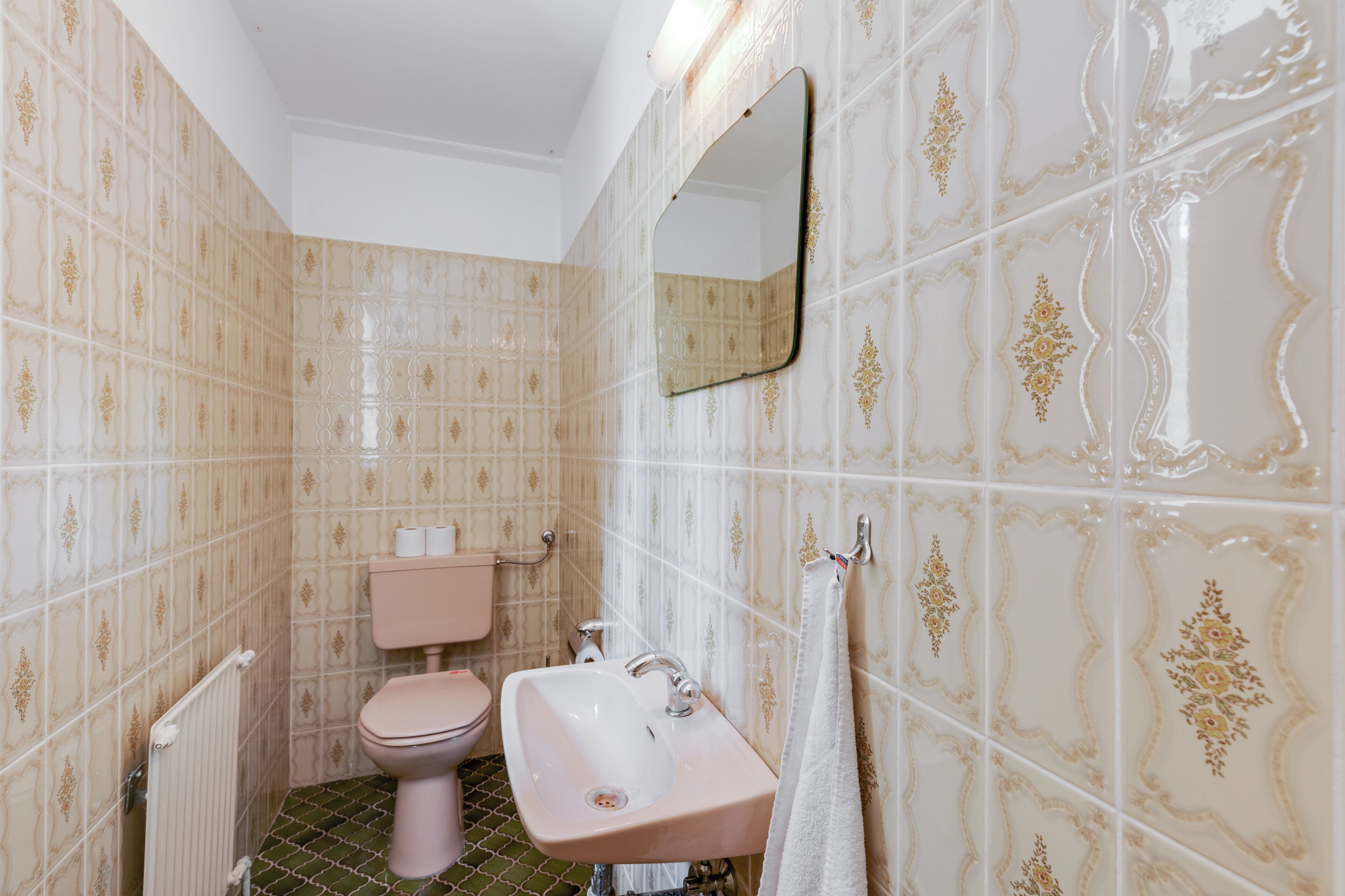 A bathroom with a toilet, sink, and mirror.