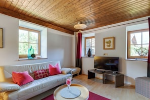 A living room with a sofa, TV, and windows. - Ferienhaus Auwiese - Family Retreat (Lend)