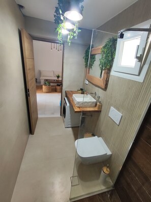 Une salle de bain avec un meuble-lavabo en bois, un lavabo blanc, un miroir et un espace douche.