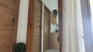 Una puerta de madera, un espejo y una pequeña planta en maceta.