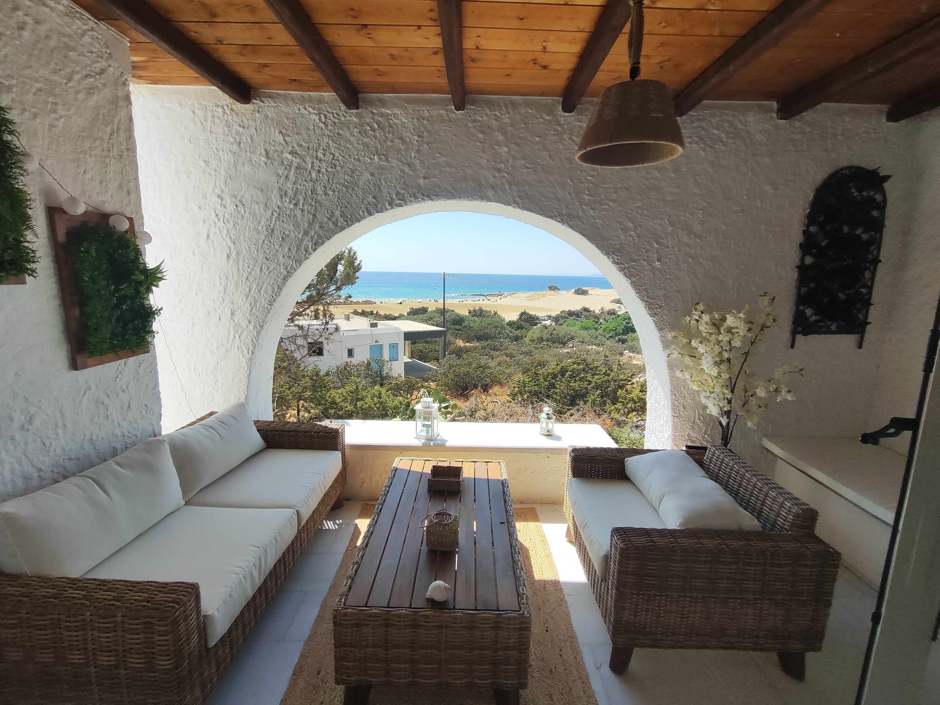 Ein überdachter Außenbereich mit Blick auf den Strand und die Gebäude.. Irini's Home Sea View Naxos Dream by ΜΡS