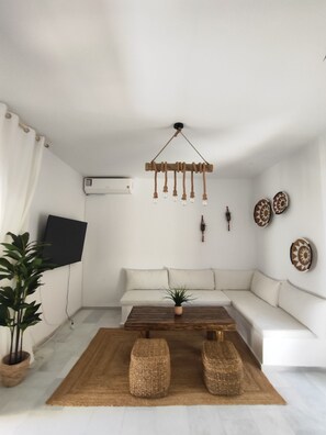 A modern living room with a white sofa, a wooden coffee table, and a hanging light fixture. - Irini's Home Sea View Naxos Dream by ΜΡS (Pirgaki)