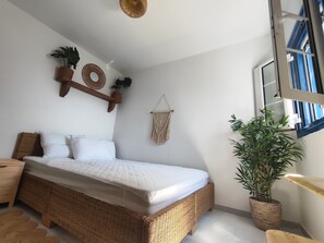 A room with a wicker bed, a macrame wall hanging, and a potted plant. - Irini's Home Sea View Naxos Dream by ΜΡS (Pirgaki)