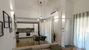 A modern living room with a sofa, dining area, kitchen, and a view of the outdoors. - Apartment in villa with veranda and private pool (Castellammare del Golfo)
