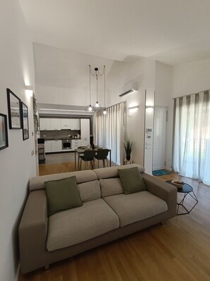 Ein modernes Wohnzimmer mit Sofa, Essbereich, Küche und Blick ins Freie.