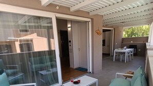 An open-plan living area with a sliding glass door leading to a balcony, a dining table with chairs, and a ceiling fan. - Apartment in villa with veranda and private pool (Castellammare del Golfo)
