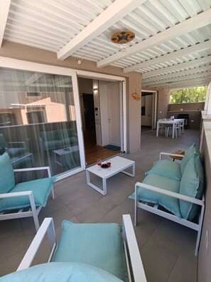 Ein offener Wohnbereich mit einer Glasschiebetür, die auf einen Balkon führt, einem Esstisch mit Stühlen und einem Deckenventilator.