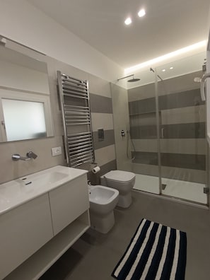 Ein modernes Badezimmer mit Waschbecken, Toilette, Bidet und einer Duschkabine.
