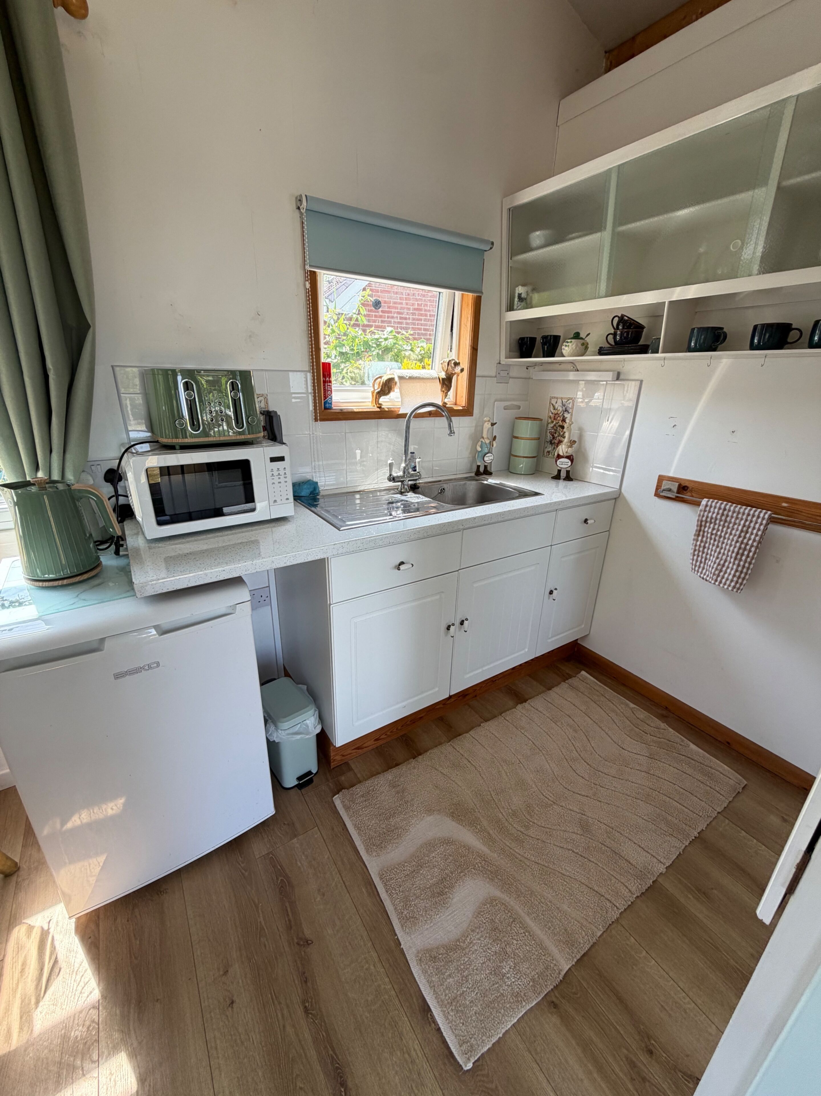 A compact kitchen with a microwave, toaster, sink, and a small refrigerator.
