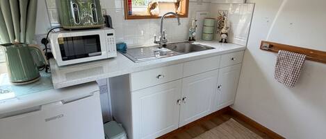 A compact kitchen with a microwave, toaster, sink, and a small refrigerator.