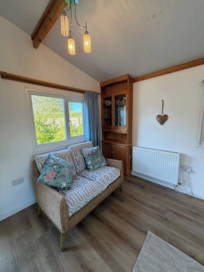 A cozy room with a wicker sofa, a wooden cabinet, a radiator, and a window with curtains.