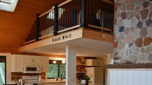 A cozy living room with a sofa, a fireplace, and a kitchen in the background. - Arla’s Pond Cottage - Scandinavian-Inspired Luxury in the Heart of Crosslake, MN (Crosslake)