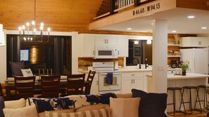 A spacious living area with a sofa, a dining table, and a kitchen in the background. - Arla’s Pond Cottage - Scandinavian-Inspired Luxury in the Heart of Crosslake, MN (Crosslake)