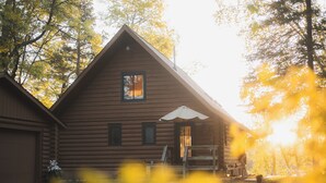 A log cabin with a pitched roof, a front porch, and a window. - Arla’s Pond Cottage - Scandinavian-Inspired Luxury in the Heart of Crosslake, MN (Crosslake)