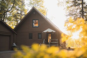 A log cabin with a pitched roof, a front porch, and a window. - Arla’s Pond Cottage - Scandinavian-Inspired Luxury in the Heart of Crosslake, MN (Crosslake)