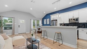 Une cuisine moderne avec des meubles blancs, un îlot central et un coin repas comprenant une table et des chaises.