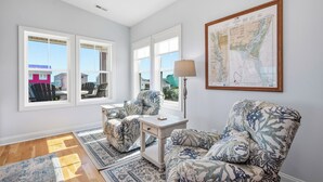 Una habitación con dos sillones estampados, una mesita de noche con una lámpara y un mapa grande enmarcado en la pared.