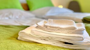 En prydligt vikt hög med vita handdukar ligger på en grön handduk.