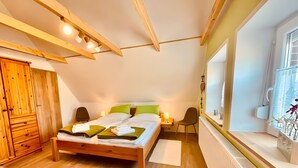 Ein Schlafzimmer mit einem hölzernen Bett, einem Nachttisch, einem Stuhl, einem Kleiderschrank und einem Fenster mit Blick.