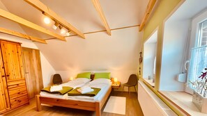 Ein Schlafzimmer mit einem hölzernen Bett, einem Nachttisch, einem Stuhl, einem Kleiderschrank und einem Fenster mit Blick.