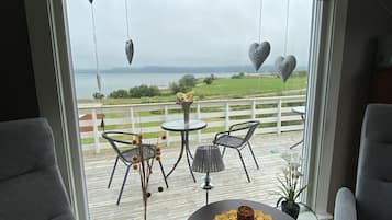 Ein Zimmer mit Seeblick, ein Tisch mit Fernbedienung und grau gepolsterte Sessel.