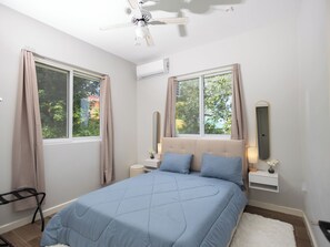 Una camera da letto con un letto, due comodini, una ventola a soffitto e finestre con tende.