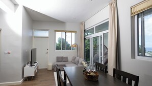 A modern dining area with a wooden table, chairs, a TV, and a sofa.