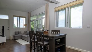 A modern living room with a dining area, large windows, and a view of the outdoors.