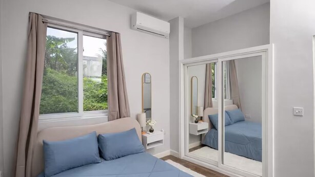 A bedroom with a bed, a nightstand, a mirror, and a wardrobe.