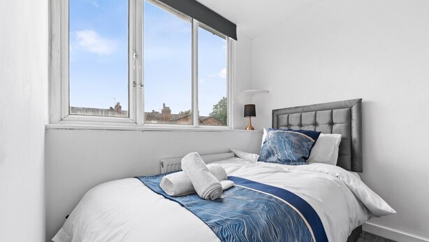 Um quarto com cama, janela e abajur.