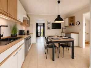 Eine moderne Küche mit Holzschränken, einer schwarzen Arbeitsplatte und einem Essbereich mit Tisch und Stühlen.