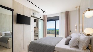 A modern hotel room with a large bed, a flat-screen TV, a balcony with a view, and a minimalist decor. - Villa Freedom (Čista Velika)