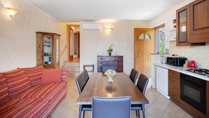 Un comedor con una mesa y sillas de madera, un sofá, y una cocina con armarios y electrodomésticos.