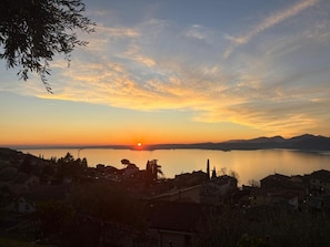 A sunset over a calm lake with buildings in the foreground.