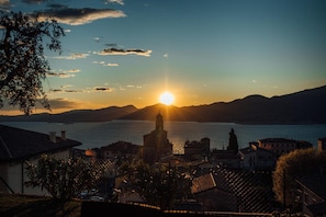 A coastal town at sunset with a prominent church, calm water, and distant mountains.
