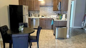 Una cucina compatta con zona pranzo, elettrodomestici in acciaio inossidabile e pavimento piastrellato.