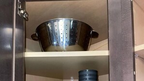 Un pensile da cucina con un colapasta, una ciotola, una tazza e due ciotole impilate.