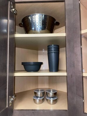 Ein Küchenschrank mit einem Sieb, einer Schüssel, einer Tasse und zwei gestapelten Schüsseln.
